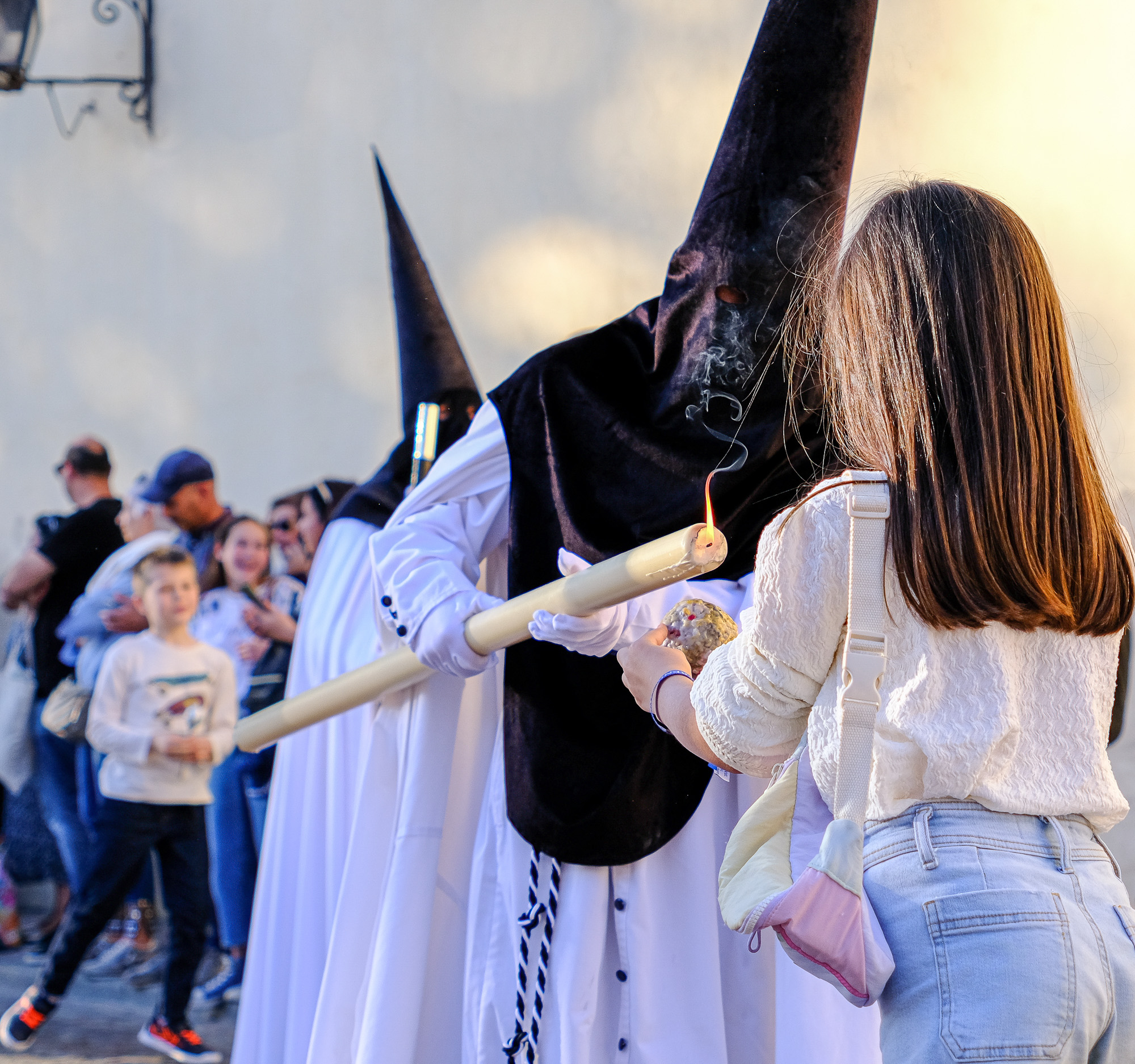 Little girl and penitent with a candle in Semana Santa processionsin Cordoba Andalusia